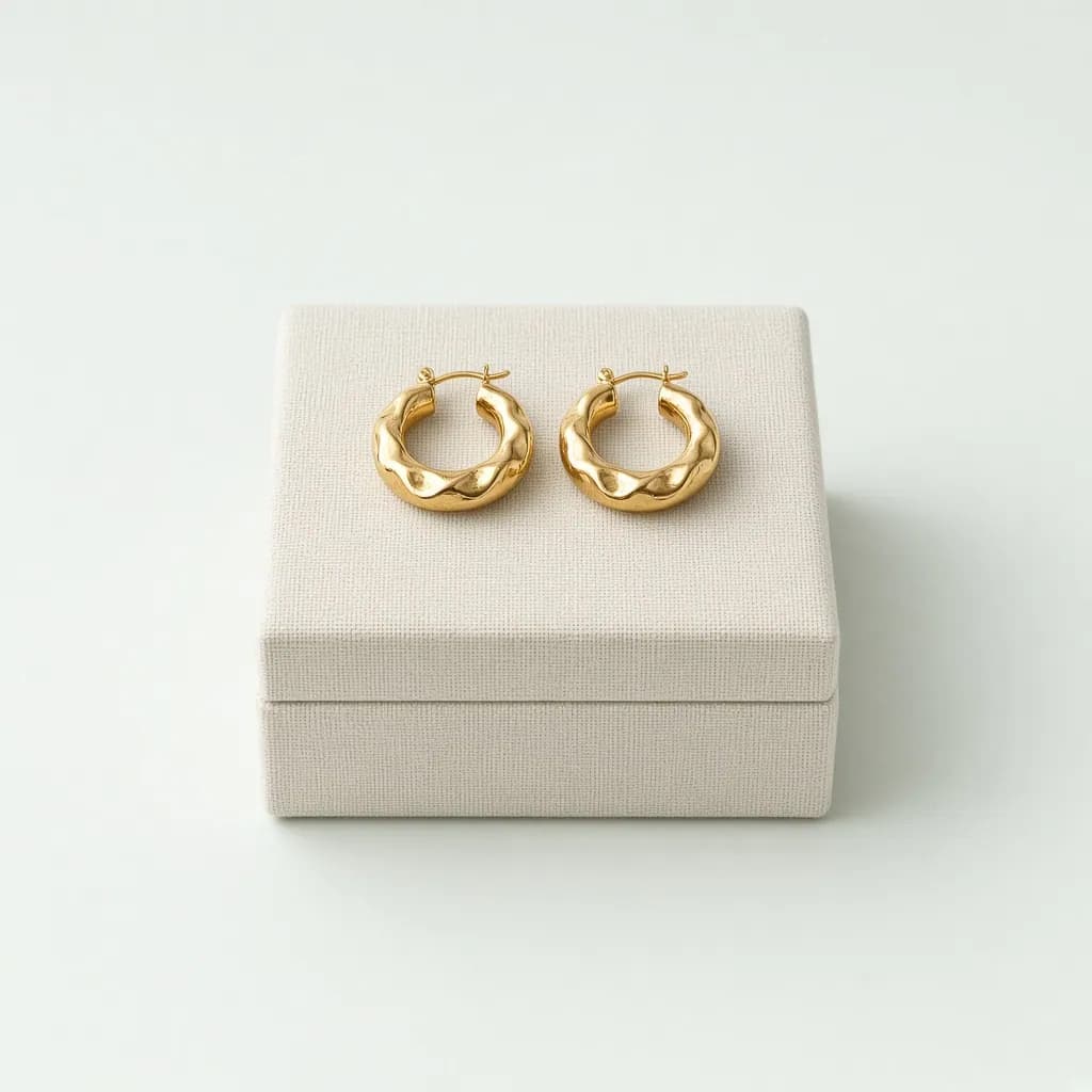 Pair of chunky gold hoop earrings on a small linen jewelry box
